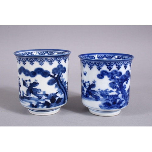 340 - A PAIR OF JAPANESE MEIJI PERIOD BLUE & WHITE PORCELAIN CUPS, each decorated with boys in landscaped ... 