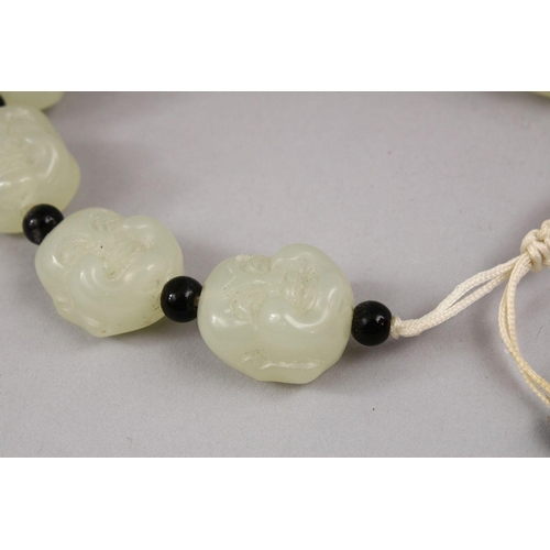 409 - A SET OF CHINESE CARVED CELADON JADE BEAD BRACELETS, the beads carved in the form of buddhas faces w... 