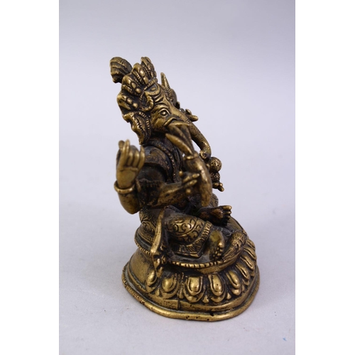 411 - A SMALL 19TH / 20TH CENTURY INDIAN BRONZE FIGURE OF GANESH, in a seated position holding multiple ob... 