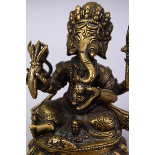 411 - A SMALL 19TH / 20TH CENTURY INDIAN BRONZE FIGURE OF GANESH, in a seated position holding multiple ob... 