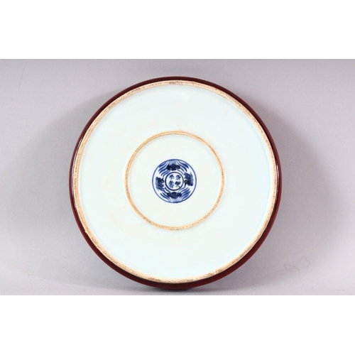 436 - A MING STYLE COPPER RED CIRCULAR PORCELAIN DISH, the central blue and white panel painted with lotus... 