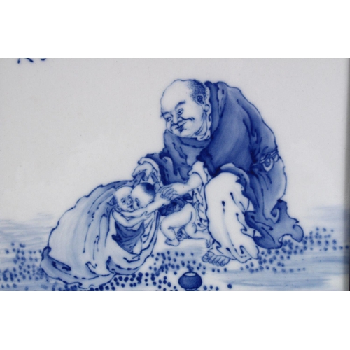 441 - A GOOD CHINESE BLUE & WHITE PORCELAIN FRAMED TILE OF LUOHAN AND CHILDREN, in a landscape setting, th... 