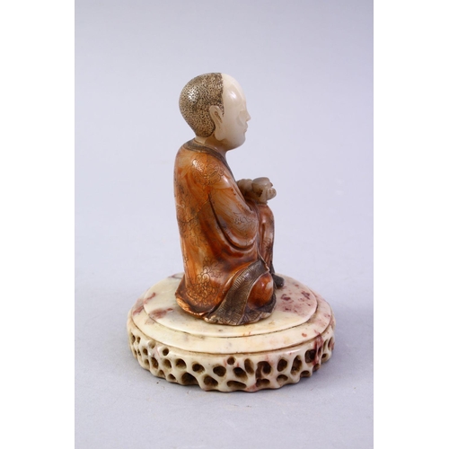 472A - A GOOD CHINESE CARVED SOAPSTONE FIGURE OF ROHAN, in a seated position holding a vessel, with a carve... 