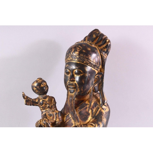 480 - A CHINESE CAST BRONZE FIGURE OF A BEARDED SAGE, holding a small boy in his arms, with traces of gild... 