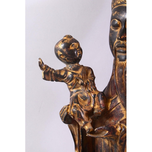 480 - A CHINESE CAST BRONZE FIGURE OF A BEARDED SAGE, holding a small boy in his arms, with traces of gild... 