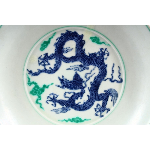 504 - A CHINESE FAMILLE VERTE /  DOUCAI PORCELAIN DRAGON DISH, with a five claw dragon amongst clouds, the... 