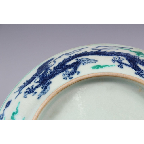 504 - A CHINESE FAMILLE VERTE /  DOUCAI PORCELAIN DRAGON DISH, with a five claw dragon amongst clouds, the... 