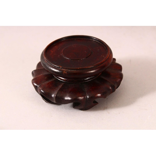 54 - A GOOD JADE CUP on a wooden stand. 2.5ins diameter.