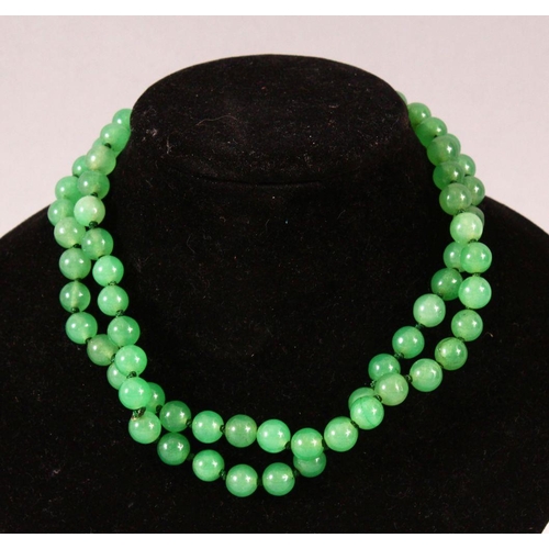 63 - A STRING OF JADE BEADS, 66cm long.