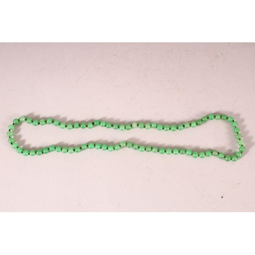 63 - A STRING OF JADE BEADS, 66cm long.