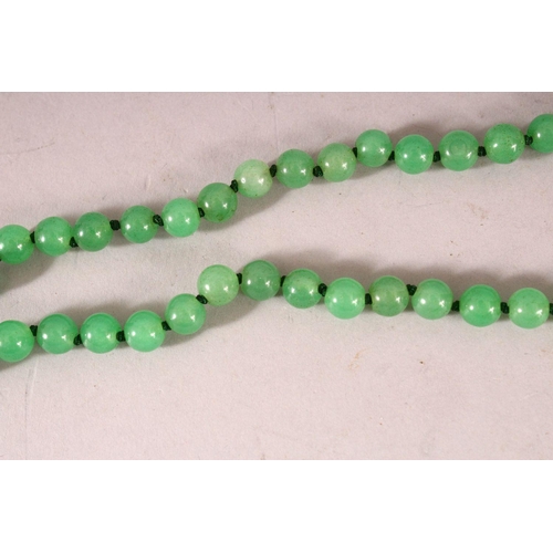 63 - A STRING OF JADE BEADS, 66cm long.