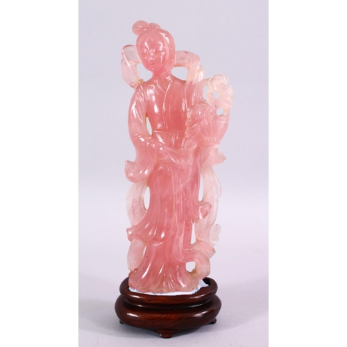 67 - A CHINESE CARVED ROSE QUARTZ FIGURE OF GUANYIN, stood holding a bouquet of flora, on a carved wooden... 