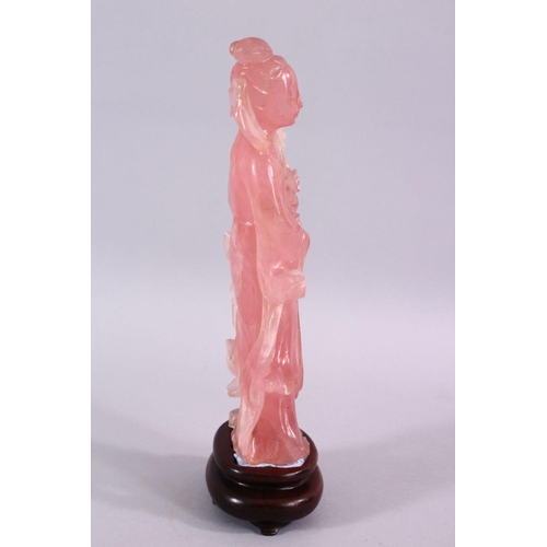 67 - A CHINESE CARVED ROSE QUARTZ FIGURE OF GUANYIN, stood holding a bouquet of flora, on a carved wooden... 