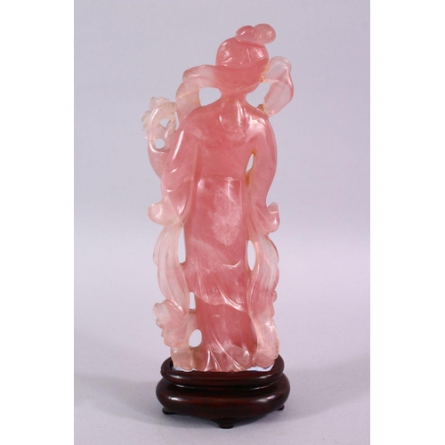 67 - A CHINESE CARVED ROSE QUARTZ FIGURE OF GUANYIN, stood holding a bouquet of flora, on a carved wooden... 