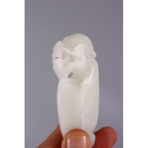 69 - A CHINESE CARVED WHITE JADE DOG PENDANT, carved in the form of a lion / temple dog, 8cm