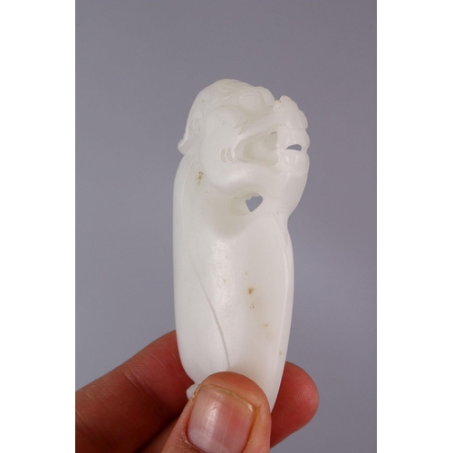 69 - A CHINESE CARVED WHITE JADE DOG PENDANT, carved in the form of a lion / temple dog, 8cm