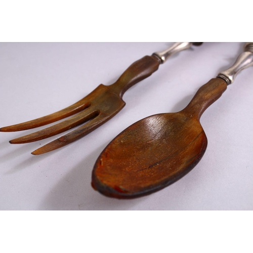 73 - A 19TH CENTURY RHINOCEROS HORN & SILVER SALAD SERVING SPOONS, 30cm.