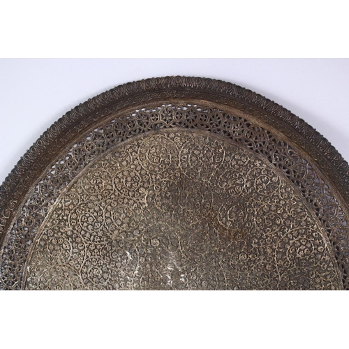 792 - A LARGE INDIAN SILVERED BRONZE OR BRASS TRAY, with a central crest and scrolling foliate, 68.5cm x 5... 