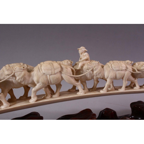 821 - AN UNUSUAL EARLY 20TH CENTURY CARVED IVORY TUSK BRIDGE, on wooden stand, carved as a group of eleven... 