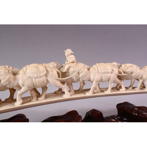 821 - AN UNUSUAL EARLY 20TH CENTURY CARVED IVORY TUSK BRIDGE, on wooden stand, carved as a group of eleven... 