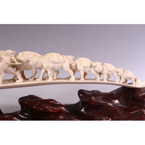 821 - AN UNUSUAL EARLY 20TH CENTURY CARVED IVORY TUSK BRIDGE, on wooden stand, carved as a group of eleven... 