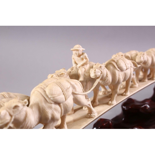 821 - AN UNUSUAL EARLY 20TH CENTURY CARVED IVORY TUSK BRIDGE, on wooden stand, carved as a group of eleven... 