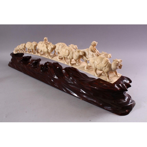 821 - AN UNUSUAL EARLY 20TH CENTURY CARVED IVORY TUSK BRIDGE, on wooden stand, carved as a group of eleven... 