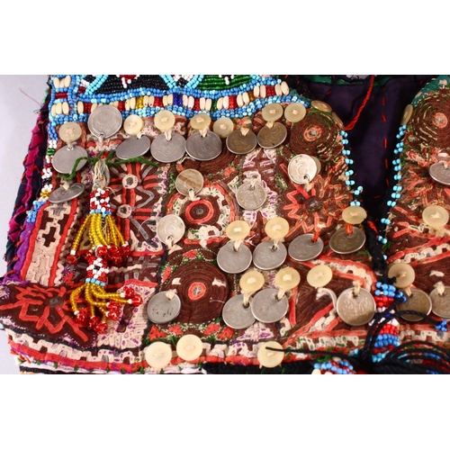 843 - A BALOCHISTAN HEAD DRESS, adorned with coins, rings, beads etc. together with associated overshirt.