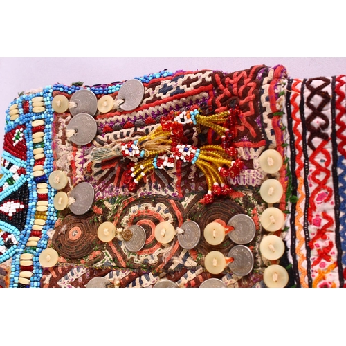 843 - A BALOCHISTAN HEAD DRESS, adorned with coins, rings, beads etc. together with associated overshirt.