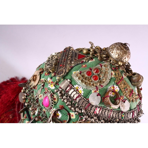 843 - A BALOCHISTAN HEAD DRESS, adorned with coins, rings, beads etc. together with associated overshirt.