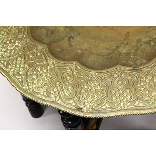 853 - A GOOD LARGE ISLAMIC BRASS TRAY TABLE AND FOLDING STAND, with embossed decoration, 76cm diameter.