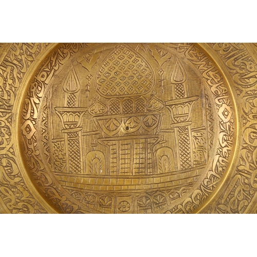 858 - A 19TH CENTURY PERSIAN ENGRAVED CALLIGRAPHIC BRASS DISH, with bands of calligraphy and temple scenes... 