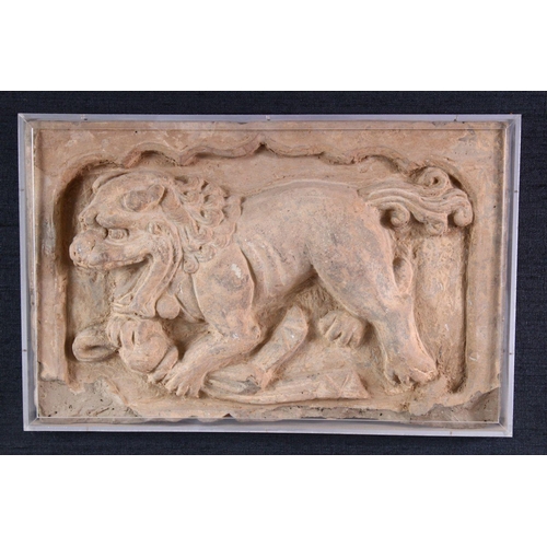 864 - A CHINESE SANDSTONE RELIEF PANEL depicting a Buddhistic lion, framed. 20cms x 31cms.