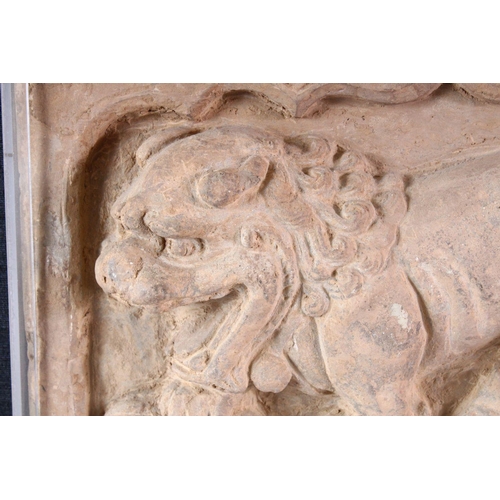 864 - A CHINESE SANDSTONE RELIEF PANEL depicting a Buddhistic lion, framed. 20cms x 31cms.