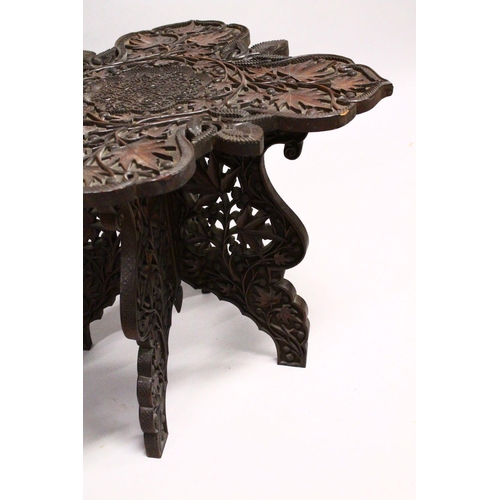 872 - A GOOD EARLY 20TH CENTURY BURMESE HARDWOOD TABLE, the shaped top and folding base, profusely carved ... 