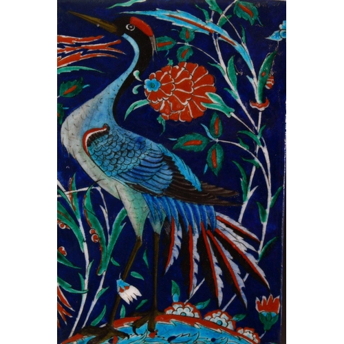 882 - TWO IZNIK TILES, one painted with a heron, one with stylised flowers, both 24cm x 16cm.