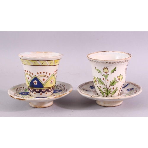 884 - TWO ISLAMIC POTTERY CUPS AND SAUCERS, with floral and geometric decoration.