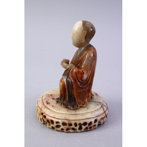 186 - A GOOD CHINESE CARVED SOAPSTONE FIGURE OF ROHAN, in a seated position holding a vessel, with a carve... 