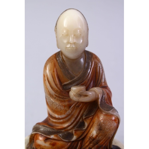 186 - A GOOD CHINESE CARVED SOAPSTONE FIGURE OF ROHAN, in a seated position holding a vessel, with a carve... 