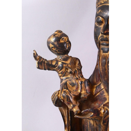 211 - A CHINESE CAST BRONZE FIGURE OF A BEARDED SAGE, holding a small boy in his arms, with traces of gild... 