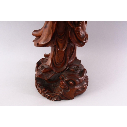 349 - A GOOD LARGE CHINESE CARVED WOOD FIGURE OF GUANYIN, standing on a dragon, 55cm high.