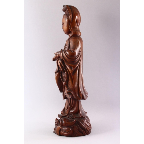 349 - A GOOD LARGE CHINESE CARVED WOOD FIGURE OF GUANYIN, standing on a dragon, 55cm high.