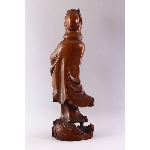 349 - A GOOD LARGE CHINESE CARVED WOOD FIGURE OF GUANYIN, standing on a dragon, 55cm high.