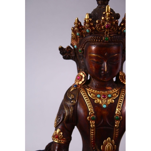 49 - A CHINESE GILT BRONZE INLAID FIGURE OF A DEITY / BUDDHA, in a seated position with an object in hand... 