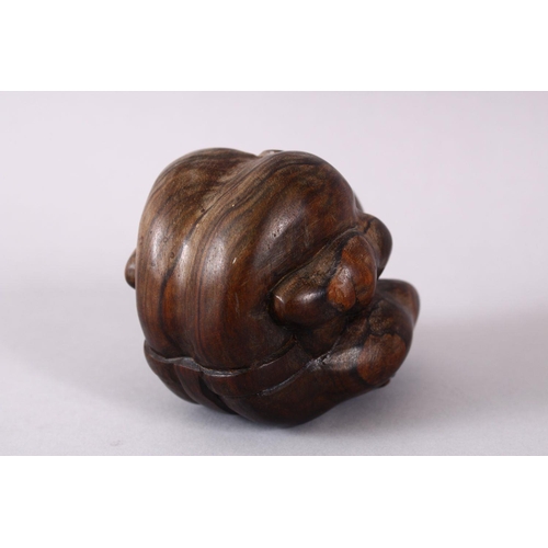 63 - AN ORIENTAL CARVED HARDWOOD FIGURE OF A FIGURE, in a seated downward position with its hands coverin... 