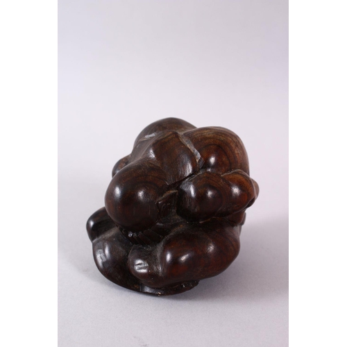 63 - AN ORIENTAL CARVED HARDWOOD FIGURE OF A FIGURE, in a seated downward position with its hands coverin... 