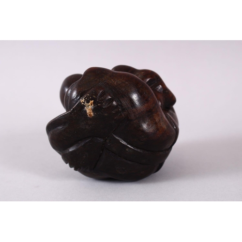 63 - AN ORIENTAL CARVED HARDWOOD FIGURE OF A FIGURE, in a seated downward position with its hands coverin... 