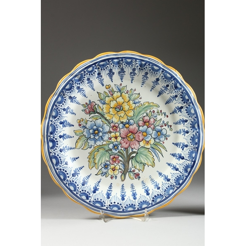 23 - TWO POTTERY DISHES painted with flowers, 13 in. diameter.