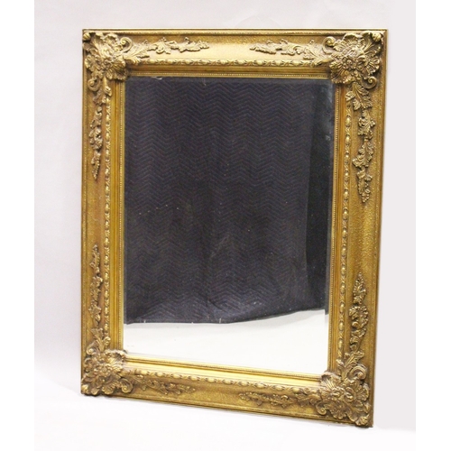 3 - A LARGE GILT BEVELLED MIRROR with scrolling decoration, 5 ft. 3 in.  high, 4 ft. 2 in. wide.