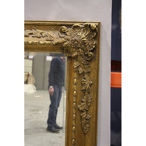 3 - A LARGE GILT BEVELLED MIRROR with scrolling decoration, 5 ft. 3 in.  high, 4 ft. 2 in. wide.